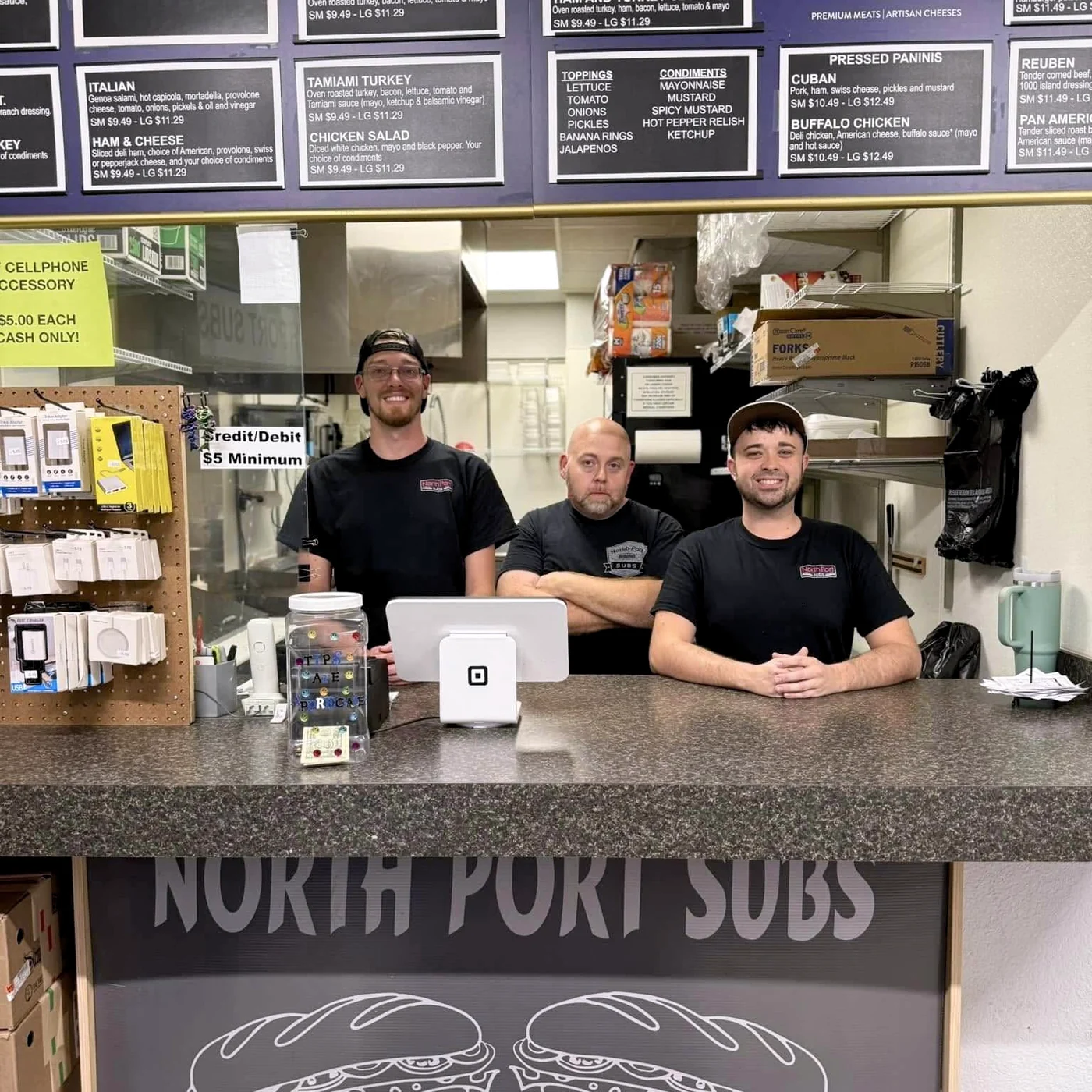 Three members of the North Port Subs crew behind the shop counter